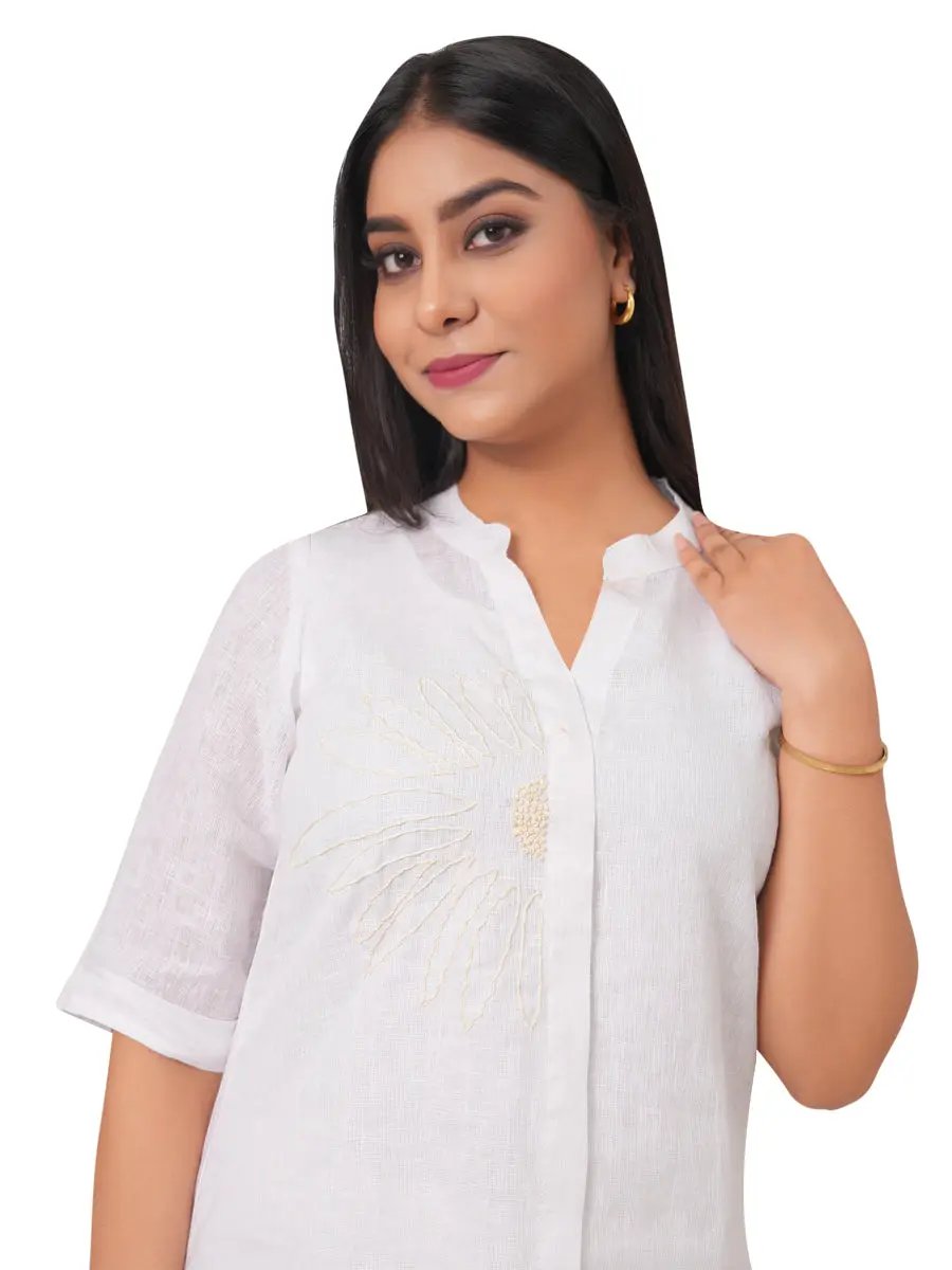 Woman wearing a white blouse with intricate designs on a white background