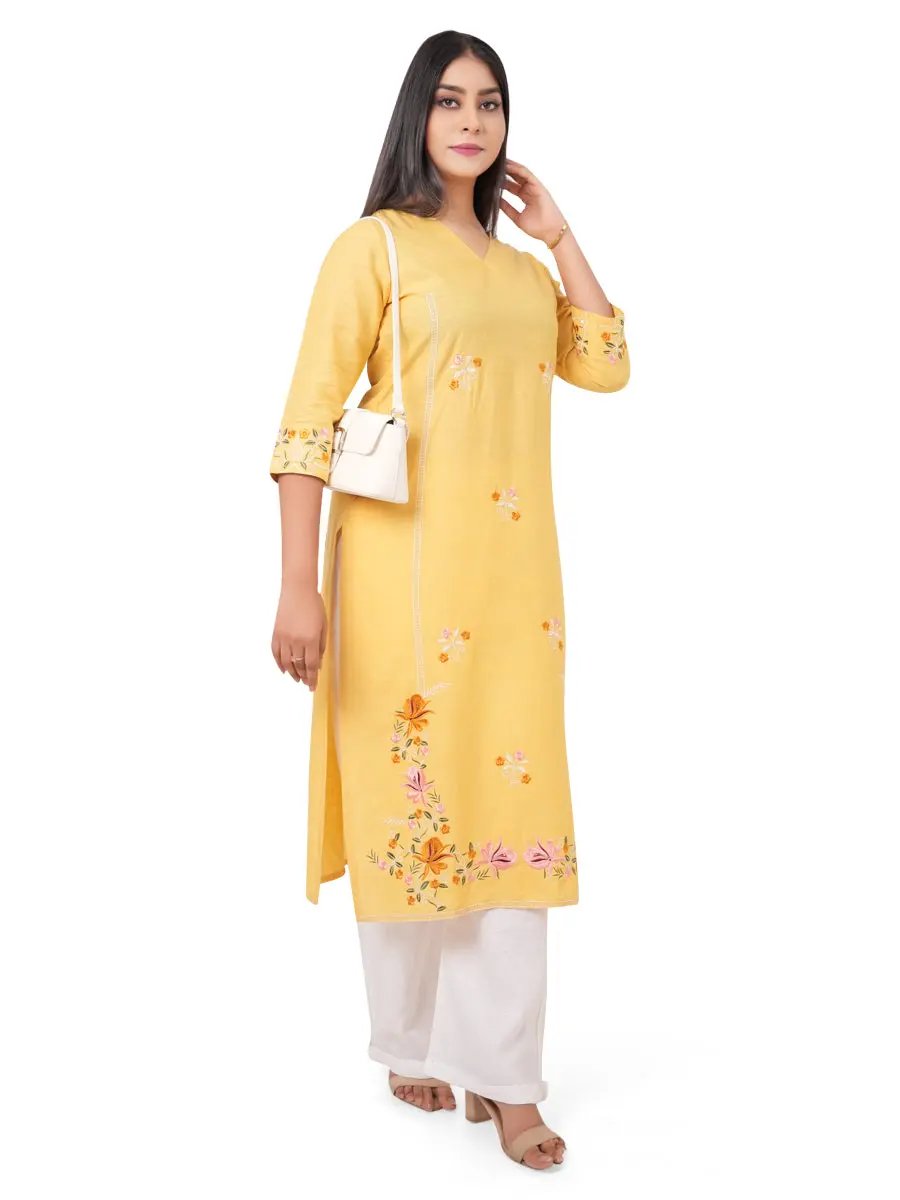 A woman wearing a yellow kurti with floral embroidery on a white background