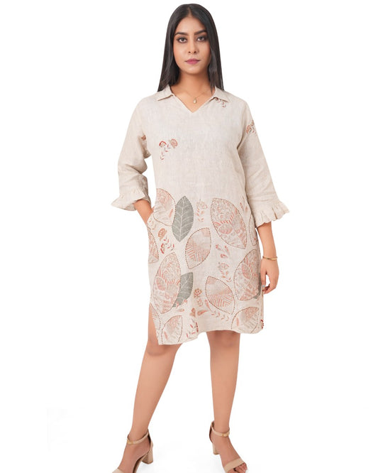 Woman wearing a pure linen beige dress with floral patterns on a white background