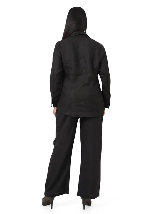 Person wearing a black linen co-ord set standing against a white background, back view