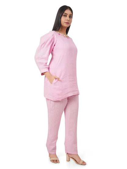 Woman wearing a pink pure linen co-ord set on a white background in side view