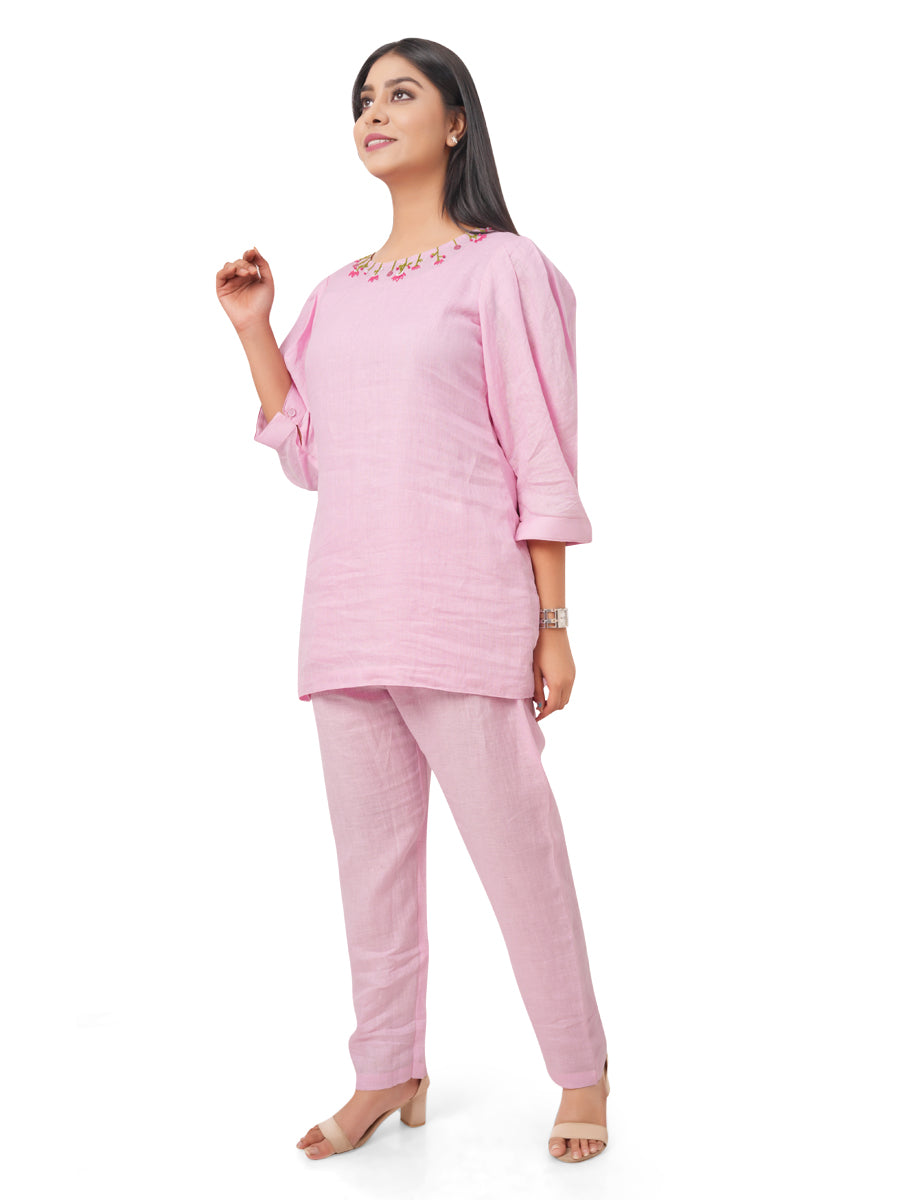 Woman wearing a pink linen co-ord set with a white background