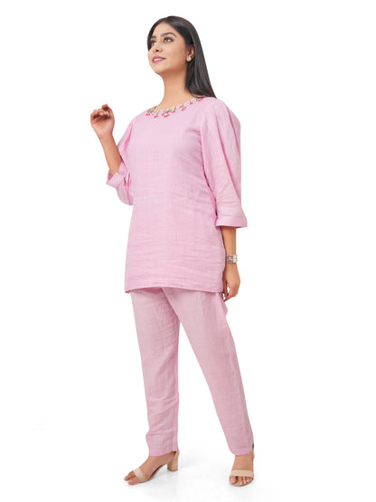 Woman wearing a pink linen co-ord set with a white background