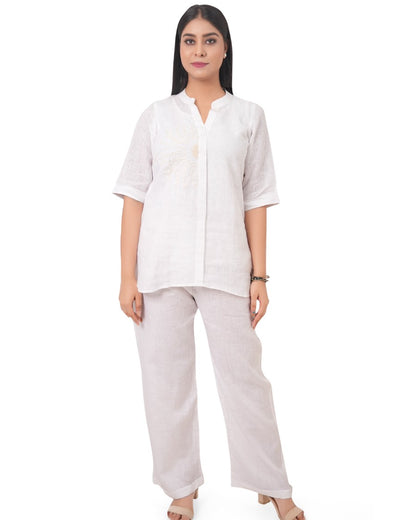 Woman wearing a white linen shirt and beige linen pants on a white background