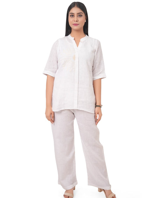 Woman wearing a white linen shirt and beige linen pants on a white background