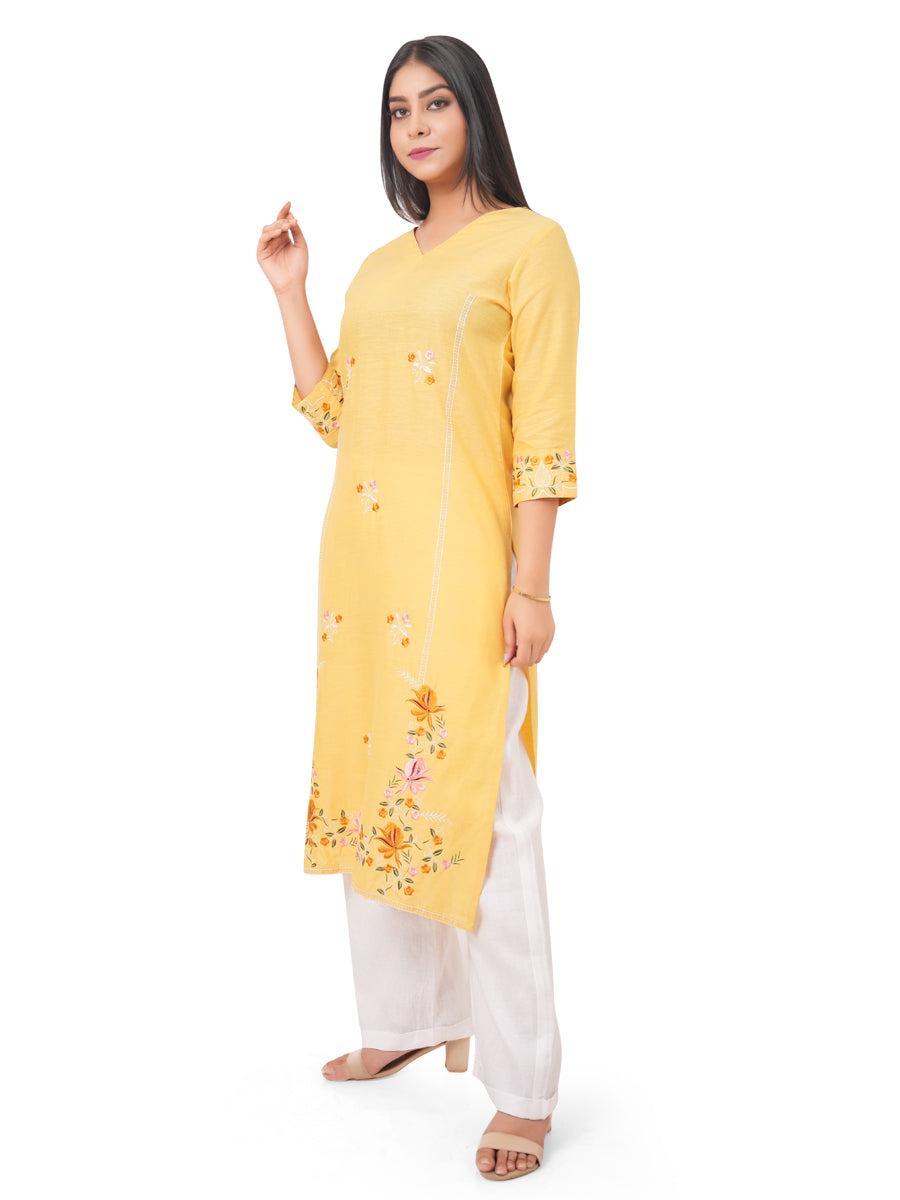 A woman wearing a yellow linen kurti with floral patterns on a white background