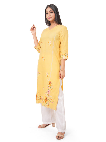 A woman wearing a yellow linen kurti with floral patterns on a white background