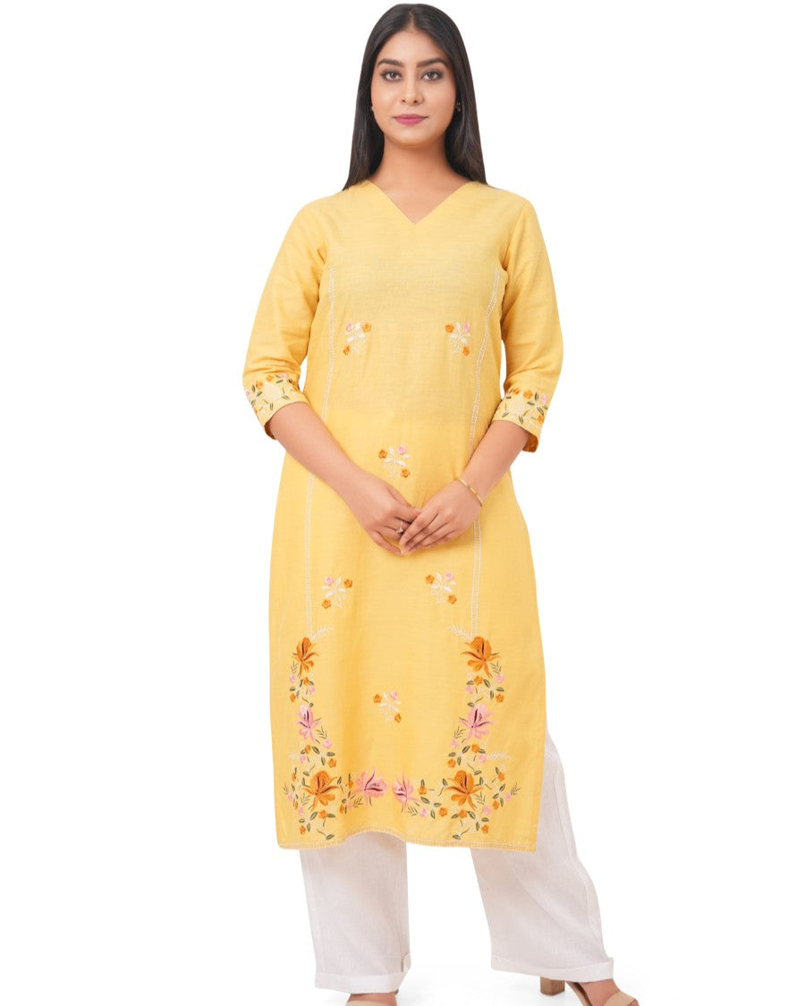 A woman wearing a yellow embroidered linen kurti with white pants on a white background